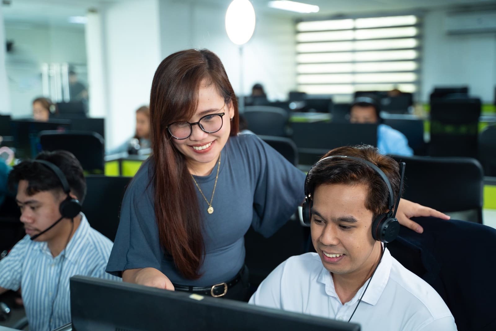 A Metacom team lead assisting a recruiter at their desk in the office